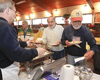 The Vindicator/Lisa-Ann Ishihara -- Gary Robinson of Warren fills the plates of Tim Austin and Art Kantner at Aulizio's Banquet Center in Warren for the free christmas dinner