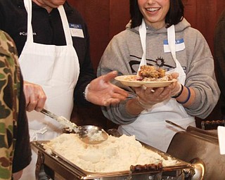 The Vindicator/Lisa-Ann Ishihara -- Gary Robinson of Warren and Sara Stassinis of Cortland fills the plates attendants at Aulizio's Banquet Center in Warren for the free christmas dinner. Sara said she "wants everyone to know that this holiday we should remember in our hearts that Jesus is our lord and savior and its a blessing to help all of these beautiful people. "