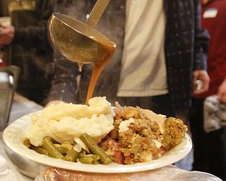 The Vindicator/Lisa-Ann Ishihara -- Ryan Saylor of Niles pours gravy on top of a dinner plate at Aulizio's Banquet Center in Warren for the free christmas dinner