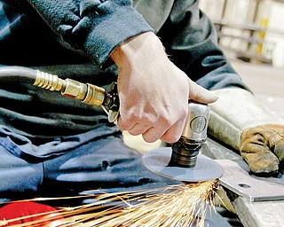 Brian Rowe of Backyard Buddy in Warren uses a grinder to shape parts for an auto lift.