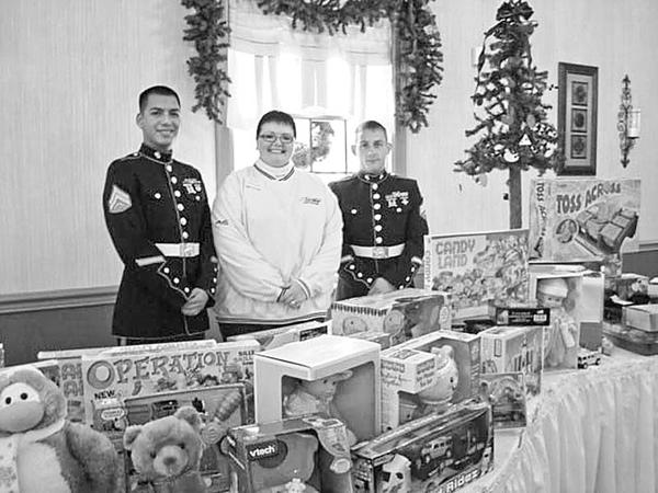 Special to The Vindicator
FOR THE CHILDREN: Canfield Women’s Club collected toys for the Toys for Tots campaign conducted by the U.S. Marine Corps during a Christmas social recently at A La Cart Catering in Canfield. Above are, from left, Marine Corps corporals Noe Estrada and Randy Kibler as they accept the gifts for the children and receive a check, the proceeds of a basket raffle, from Sarah Graziani, chair of the club’s Caring for America Program. Entertainment at the gathering was provided by the Silver Strings of Canfield.