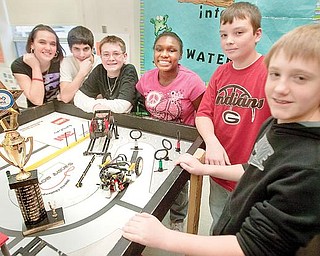 SMILES ALL AROUND: Members of the Lego Lizards of Girard Junior High School gather around the board on which “Lizzy,” the team’s robot travels. Students, from left, are Gabby Cloggins, Nick Sherock, Cameron Blenton, Jalene McClendon, Brian Spence and David Kuzman. They won the Quality Design Award in the FIRST Lego League regional competition in Canton. The trophy is at left.  