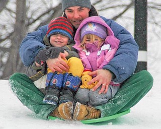 While Mahoning Valley drivers were cursing the white stuff coating area roads Thursday, some kids managed to find the silver lining in the snow clouds that blanketed the Northeast. Above, Adam Gardner, with his children Caleb, 4, and Sophie, 2, all of Warren, slide down a snowy hill at Packard Park in Warren. 