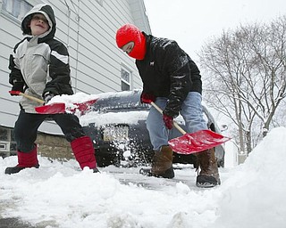Brothers Declan, 7, left, and Isaiah Sekol shovel the driveway of their Struthers home on Maplewood Friday morning.