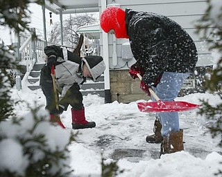 Brothers Declan, 7, left, and Isaiah Sekol shovel the driveway of their Struthers home on Maplewood Friday morning.