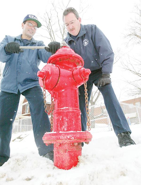 SNOW JOB: Girard Fire Capt. Salvatore “Sal” Ponzio, left, shows how a wrench is used to access a fire hydrant as firefighter Jim Quinn lends a hand. Girard water department maintains the hydrants and citizens cooperate by reporting any problems. If a hydrant should freeze, fire trucks carry 2,000 feet of hose to reach other hydrants and also carry a water supply. 