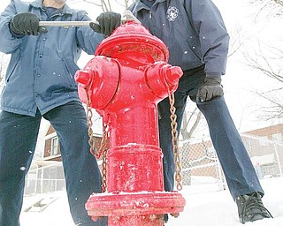 SNOW JOB: Girard Fire Capt. Salvatore “Sal” Ponzio, left, shows how a wrench is used to access a fire hydrant as firefighter Jim Quinn lends a hand. Girard water department maintains the hydrants and citizens cooperate by reporting any problems. If a hydrant should freeze, fire trucks carry 2,000 feet of hose to reach other hydrants and also carry a water supply.