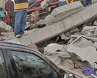 People stand on rubble along Delmas road the day after an earthquake hit Port-au-Prince, Haiti, Wednesday, Jan. 13, 2010. A 7.0-magnitude earthquake hit Haiti on Tuesday.