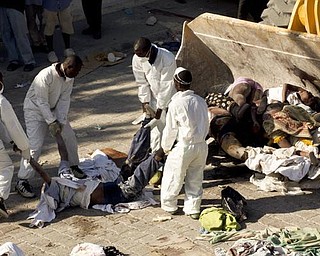 Workers move the bodies of the victims of the earthquake onto a bulldozer at the morgue in Port-au-Prince, Thursday, Jan. 14, 2010.