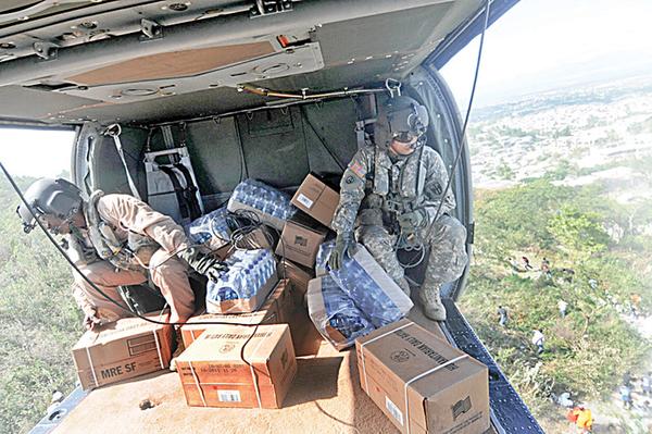 HELP FROM ON HIGH: U.S. troops drop food supplies from a helicopter as relief efforts continue throughout Port-au-Prince, Haiti. The 910th Airlift Wing at the Youngstown air base will join the humanitarian mission this week.