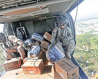 HELP FROM ON HIGH: U.S. troops drop food supplies from a helicopter as relief efforts continue throughout Port-au-Prince, Haiti. The 910th Airlift Wing at the Youngstown air base will join the humanitarian mission this week.