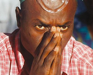 A parishioner with an aspirator mask prays during Sunday Mass outside the St. Louis King of Spain Catholic Church in Port-au-Prince, Haiti, Sunday, Jan. 17, 2010. The church was damaged during Tuesday's earthquake.