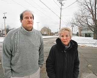 NEIGHBORHOOD WOES: Longtime South Side residents Terry Esarco, 50, left, and Maggy Lorenzi, 58, right, stand just up the street from St. Dominic Church, center, where 80-year-old Angeline Fimognari was shot and killed Saturday morning. Lorenzi said she’s lived on the South Side of Youngstown for 50 years and has seen the neighborhood deteriorate. 