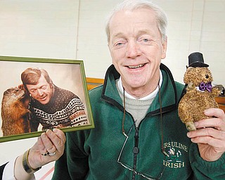 GROUNDHOG BUDDY: The Rev. Timothy O’Neill, pastor of St. Patrick Church in Hubbard, holds mementos of Groundhog Days past. The photo of him with Phil was taken in Punxsutawney about 25 years ago. 