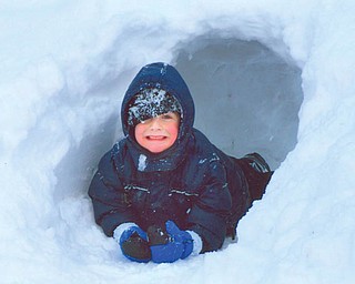 SNOW WAY OUT: Justin Mackey of Boardman exits the snow cave that he and his dad created on Spring Garden Court...