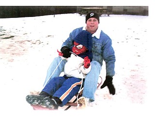 Eric Schenk and his son, Zane, of Lowellville take a ride on their old-fashioned red sled down Sled Hill in Mill Creek Park on Christmas Eve afternoon..