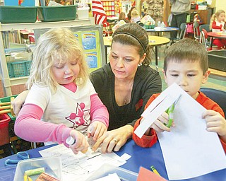 William D. Lewis/The Vindicator Ondrea Burns, a parent volunteer at Joshua Dixon Elem School in Columbiana, helps kindergarten students Briana Reyes and Keaton Surgenavic with a project at the school.