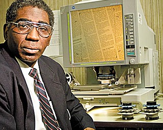 Steffon Jones sits along a microfilm machine at YSU's Maag Library. Jones and others have been using old newspaper articles and government documents to research a prominent local African American, Ferdinand H. Simpson.