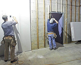 CLEAR VIEW: David Michael, left, and James Wolfe are both employees of Tri-State Glass in East Liverpool. They carried a large window into the soon-to-be Goodwill store in the Austintown Plaza. The store opening will mark the eighth Goodwill store for Youngstown Area Goodwill Industries.