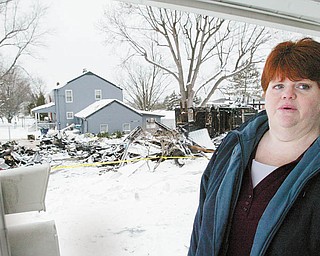 MEMORIES OF AN EXPLOSION: Jodi Hunt stands on the front porch of her home on Center Road as she recounts the events leading up to the home next door to hers exploding Saturday. The charred remains of the neighboring house can be seen in the background.