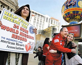 Jeff Ondash, nicknamed Teddy McHuggin, hugs a tourist as Joshua Dietrich, left, holds a sign on The Strip in Las Vegas on Saturday, February 13, 2009. Ondash set the Guinness World Record for hugs in a 24 hour period and succeeded in giving 7,777 hugs.