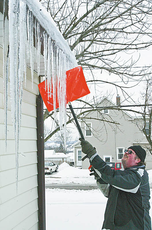 DOn’T DO THIS: David Kovach knocks down icicles on his Plymouth Street home in Girard. Roofing and gutter company officials say don’t do it to avoid possible injury and damage to your home.