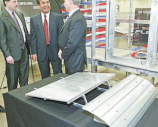 WIND TUNNEL TESTING: From left, Abraham; Ganesh Kudav, a YSU engineering professor; and Robert Voytilla, chief financial officer for Northern States Metals, discuss a wind tunnel at YSU used for testing the effectiveness of wind deflectors in the installation of rooftop solar-energy panels manufactured by Northern States. The company built the tunnel for YSU to use in the development of the deflector, a model of which is in the foreground.