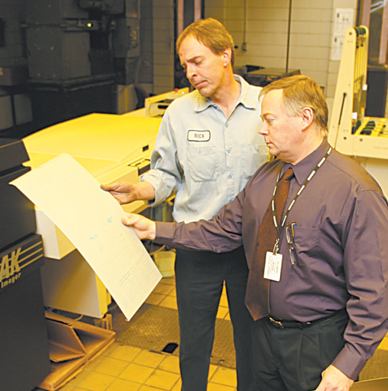 Rick Wineman, pressroom foreman, left, and Jim Davies, production
director, examine one of the plates that will be placed on the press prior to printing a page.