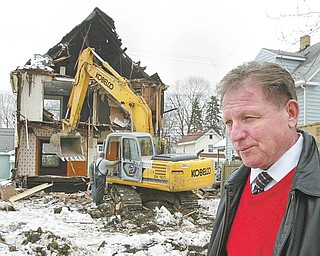 Struthers Mayor Terry Stocker watches as employees of Maverick Contractors of Lisbon demolish a house at 203 Poland Ave. in Struthers Wednesday.