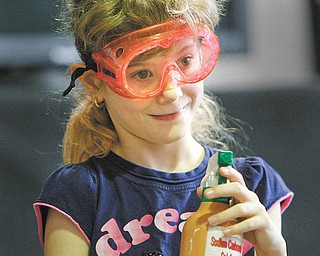 Lloyd Elementary second-grader Mercedes Willis gets ready to spray a chemical agent to find another clue in the search for the missing slime ingredients during a “Simply Chemistry” assembly with COSI.