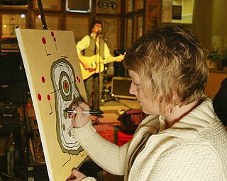 Artist Mary Farragher works on a painting while singer Simon Kenneally entertains at the Lemon Grove Café. The West Federal Street café serves up live music, local artwork, poetry readings, lecturers and discussion groups.