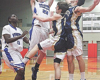 (22) Casey Carroll of Youngstown Christian goes strong to the rim as (15) Mike Mangine and (3) Pat Minnie play defense. (13) Anthony Walker watches the play during their game Tuesday night in Struthers.