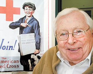 W. Russell Preston, executive director, Mahoning County Chapter of American Red Cross, says the local chapter remains active in helping people recover from disasters near and far. The chapter is celebrating its centennial this year. In the background is a vintage poster at the chapter’s Boardman headquarters.