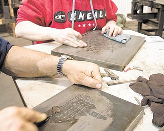 Geoffrey Hauschild|The Vindicator. Show Room Supervisor, April Powell, of Grove City, uses an EDM Stone, or synethetic sanding stone, to remove debris and pockmarks from a rescued dye at Wendell August Forge's temporary workshop in Grove City on Monday afternoon.