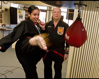 The Vindicator/Geoffrey Hauschild.Heather Powell, 17 of Youngstown, kicks a bag alongside ?Todd? Vea during a karate lesson at AE Vea Karate along Belmont Ave. on Friday afternoon.