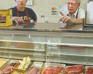 The Meating Place employee Ray Harnevious Jr., left, and store co-owner Tom Rochford discuss some of the most- popular cuts of meat sold at the Austintown butcher shop. Rochford, 74, said he and longtime friend Jack Weaver opened the store, which is stocked with a variety of chicken, beef, pork, fish and more, in 1982.