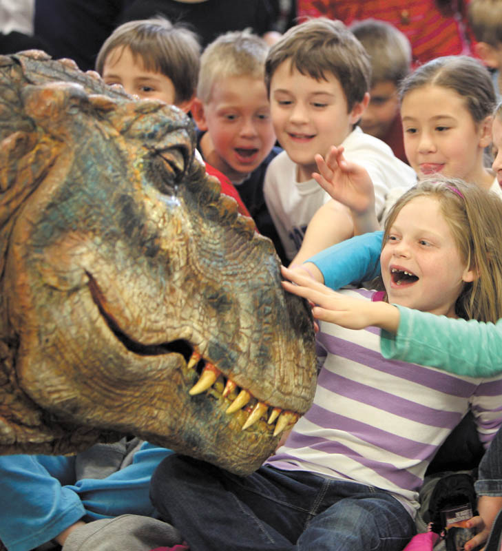 Ashlee Barth, in the striped shirt, Rachel Wolfe  and Michael Voitus pet the Baby T. Rex at the dinosaur's Mahoning Valley debut at the Poland branch of the Public Library of Youngstown and Mahoning County. Baby T., as it's called, is one of 17 life-size dinosaurs from the arena show, "Walking with Dinosaurs,Ó which runs May 4-5 at the Covelli Centre. The creature met kindergarten students from Poland's three elementary schools Monday.