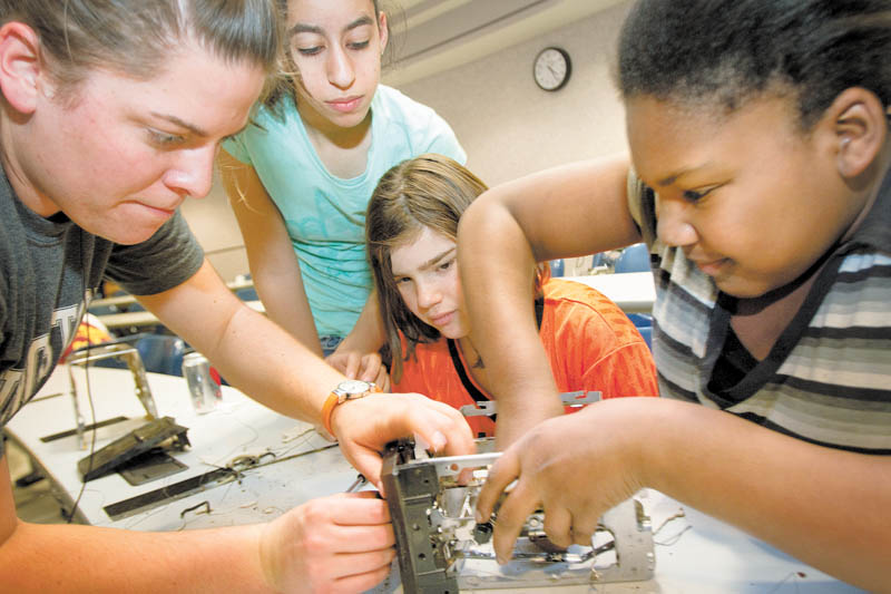 Second-year Youngstown State University civil engineering major Micelle Stipetich, from left, helps Liberty sixth-graders Haneen Kotb, 12, Jordyn Faustino, 11, and Teshaia Cain, 11, disassemble a toaster during Tear Apart A Toaster. The Thursday event at YSU's Moser Hall was arranged by the university's Society of Women Engineers. Stipetich helped organize the event.