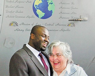 Dr. Michael K. Obeng, chief of plastic surgery at St. Elizabeth Boardman Health Center, and Kathleen M. Price, founder and director of Mission of Love, stand beneath the nose art on a C-130 Hercules cargo plane unveiled Wednesday . The 910th has transported 380,000 pounds of humanitarian aid for the Mission of Love over the last 11 years. R.E.S.T.O.R.E. Worldwide Inc., founded by Dr. Obeng, is planning a humanitarian mission to Ghana in the near future.