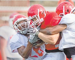 Youngstown State defenders Vance Gibbs (28) and Andre Elliot (2) put pressure on fullback Dan Banna (45) during Wednesday’s football practice at Stambaugh Stadium. Head coach Eric Wolford spent a portion of Wednesday’s practice talking about the importance of handling pressure situations and remaining composed. The Penguins will suit up for their annual spring game Saturday.