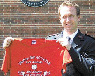 The Vindicator: Captain John Brand of the Salvation Army in Salem on .Monday displays a shirt being sold to help raise funds for the needy .next Christmas while standing by the army's large kettle..