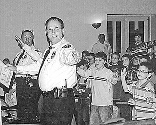 Follow the leader: Hubbard Optimist Club conducted an annual safety program in March at Roosevelt Elementary School where, from left, Hubbard Township Police Chief Todd Coonce and Hubbard City Police Chief Marty Kanetsky taught the youngsters the proper hand signals to use when riding their bikes. Every second-grader at the school received a free bike helmet. When stopped by a policeman, each biker wearing a helmet will get a ticket — for a Dairy Queen treat.