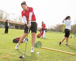 Youngstown State freshman golfer Sarah Heimlich takes a practice swing with her driver. Others at the driving range at Pine Lakes Country Club in Hubbard are junior Katie Rogner, center, and senior Ann Ciavarella.