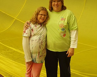 Betsy DeChristofaro and her daughter, Kaila, are standing inside of a hot air balloon that is on the ground.