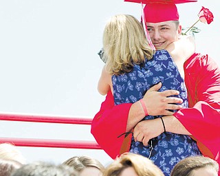 Columbiana High School graduate Michael McMaster gets a big hug from his mother, Carrie McMaster, after he presented her with a flower during commencement exercises Sunday in Harvey S. Firestone Park. High school graduations move into full swing over the next two weeks.