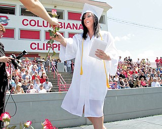 Lauren Houck walks across the stage to get a red rose after being handed her diploma during Columbiana High School's graduation program at Harvey S. FIrestone Park on Sunday. The seniors were later asked to present their flowers to a loved one in the audience who the felt helped them the most to succeed. A total of 66 students received their diplomas.