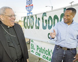 Bishop George V. Murry, bishop of the Catholic Diocese of Youngstown, left, greets Mayor Jay Williams at a 99th anniversary event for St. Patrick Church in Youngstown. The church gave away doughnuts and coffee along Market Street on Monday.