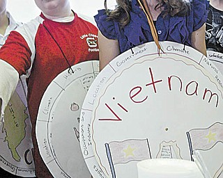 In top photograph, Ryan Kost, left, and Emily King pore over a globe during the extravaganza. Above left, Alli Moreschi dressed as a Croatian woman. Above right, Dalton Hillyer and Hannah Hum look over ethnic foods that were prepared to help the students understand the cultures of other countries.