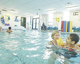 Kim Jeswald, left, a lifeguard at the Mahoning County Board of Developmental Disabilities, works with student Alphonse Green in the Leonard Kirtz School swimming pool in Austintown. The MDD board recently installed a pool cover that helps to conserve energy costs at the facility, one of the ways the board is seeking to reduce its expenditures.