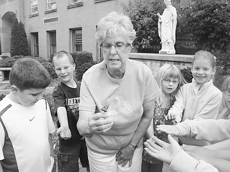 Elaine Scott, above, and members of her first-grade class at St. Patrick School in Hubbard release one of the butterflies they took care of as part of a class project. The students watch the butterflies develop and emerge from cocoons. The class then feeds and takes care of the butterflies until it’s time to release them. The project has become a tradition for first-graders.